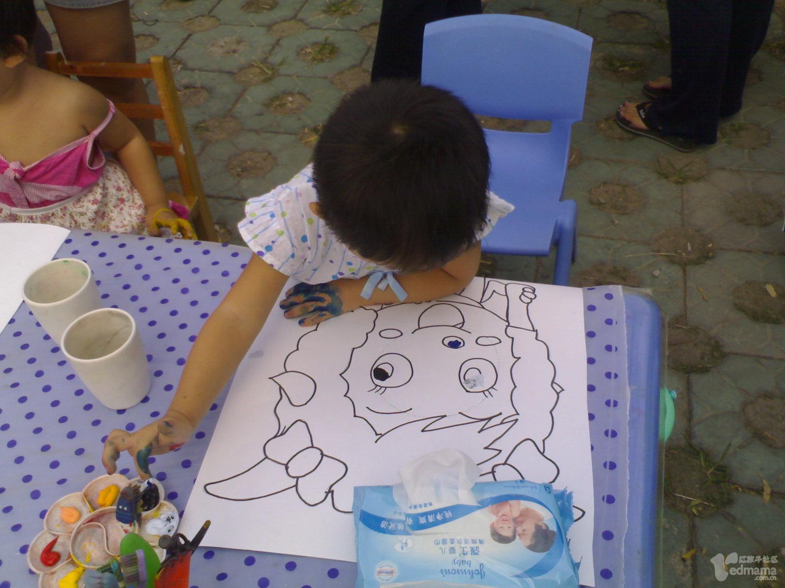 3岁的豆豆给美羊羊涂色，每个宝宝都有一张图画，颜料盘，笔和水杯，将自己与所涂鸦的作品拍照。豆豆戏称：“我把美羊羊给涂成了灰太狼!”。
