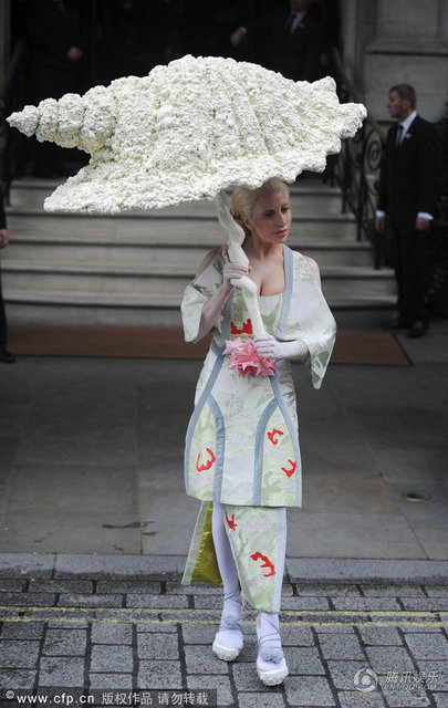 2013年11月1日英国伦敦，当地时间10月31日，Lady Gaga现身酒店外。‘雷帝’Gaga脚踩木屐似的高跟鞋，穿着似日本艺妓的她大秀乳沟，发型复古的她举着怪异的大伞难掩脸上的皱纹表情僵硬。