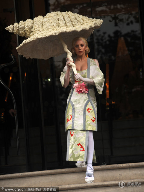 2013年11月1日英国伦敦，当地时间10月31日，Lady Gaga现身酒店外。‘雷帝’Gaga脚踩木屐似的高跟鞋，穿着似日本艺妓的她大秀乳沟，发型复古的她举着怪异的大伞难掩脸上的皱纹表情僵硬。