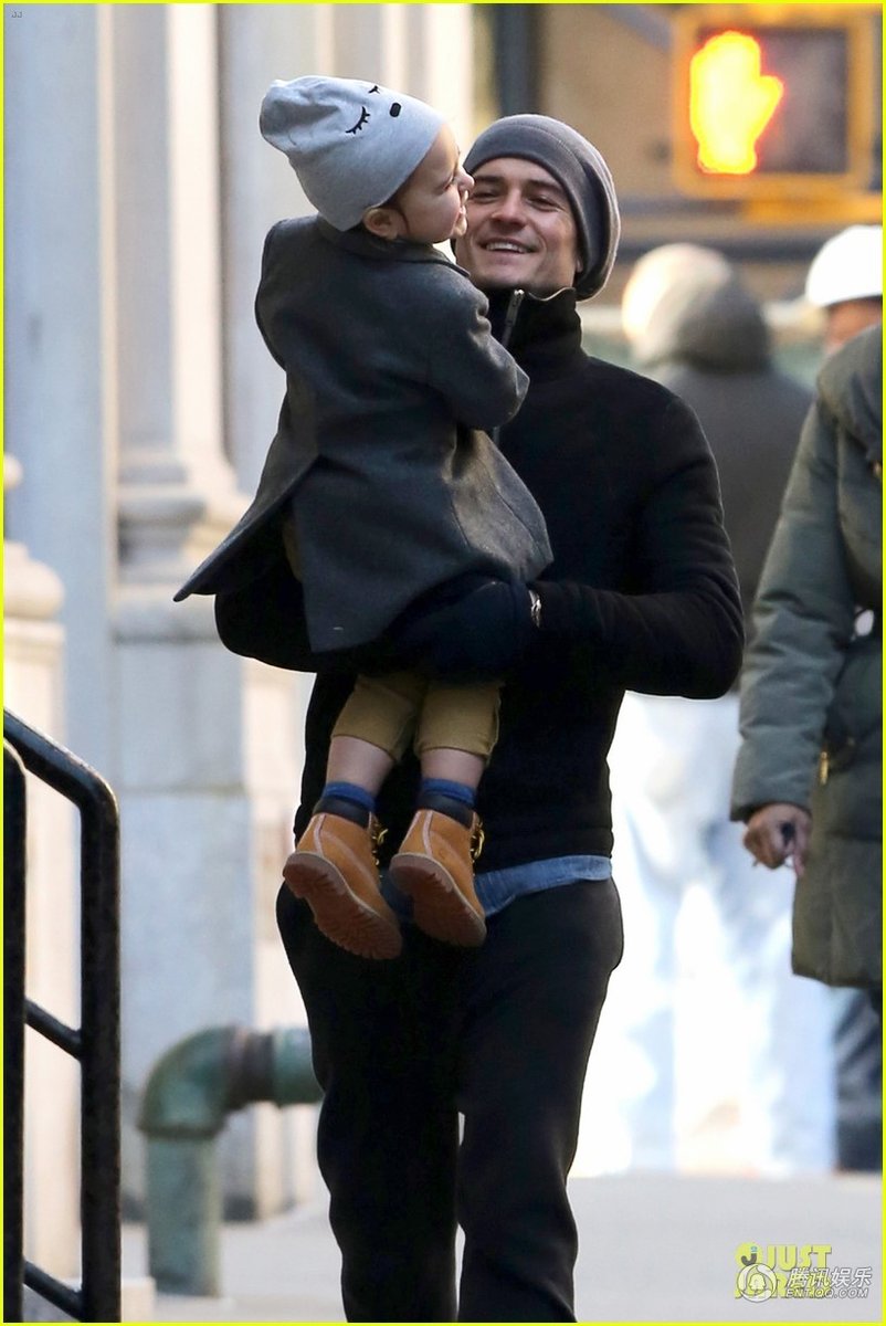 当地时间12月16日，纽约，好莱坞明星奥兰多·布鲁姆(Orlando Bloom)带着儿子弗林(Flynn)出门，他将弗林放在肩头，活泼的小家伙看到镜头调皮吐舌，在爸爸怀里开心大笑。