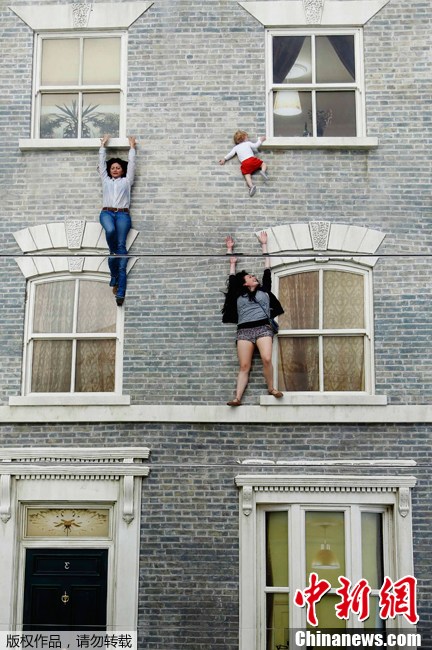 伦敦民众体验超现实“房屋” 轻松“飞檐走壁” 当地时间2013年6月25日，英国伦敦，游客们在艺术作品上摆出各种造型，仿佛“飞檐走壁”一般。只要巧妙地组合使用和控制好镜子的反射角度，能够形成很多令人惊叹的效果。阿根廷艺术家Leandro Erlich的现代艺术作品“Dalston House”就运用镜子来形成人错视觉的，在地上摆放了建筑立面模型，人在地上做各种造型，就能看到那些违反地球引力的各种视觉效果，这些都是通过四层楼高的多层镜子反射来实现的。