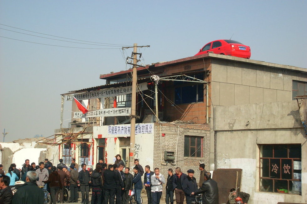 2010年3月26日，内蒙古乌海市“最牛钉子户”因和拆迁方达不成协议用吊车将一辆QQ轿车，吊到楼顶。