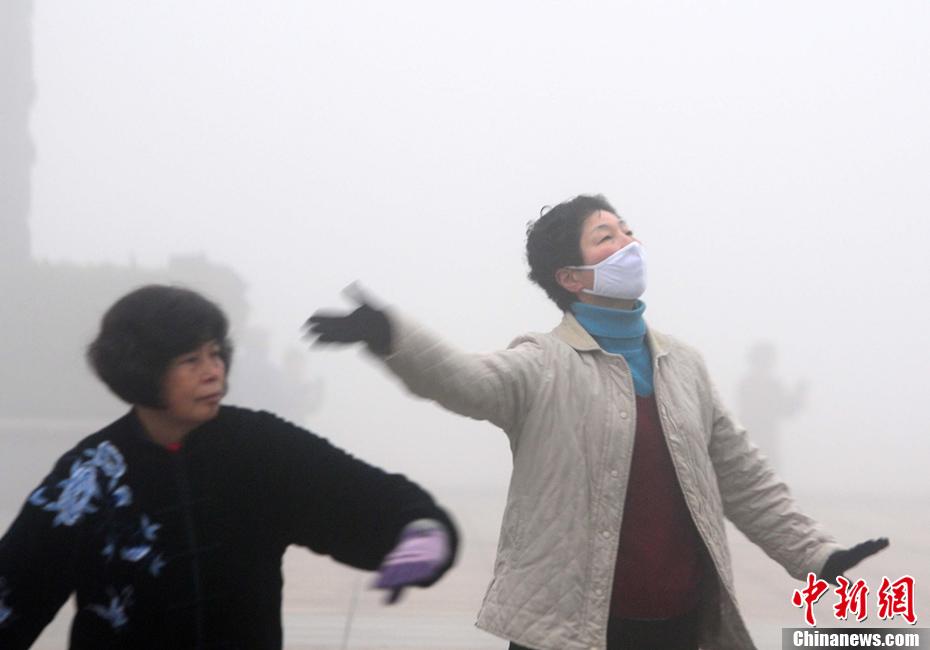 1月14日，江西九江市民戴着口罩在雾霾中晨练“打太极”。