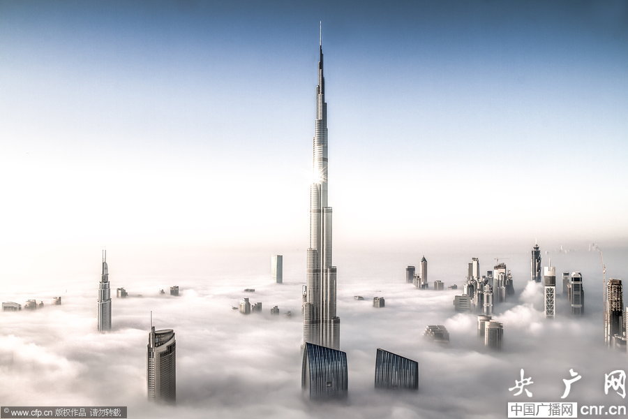 摄影师拍摄浓雾笼罩迪拜景象 迪拜，世界最高的哈利法塔在海雾笼罩中，“藐视”周边的建筑。海雾是迪拜夏冬季节转换过程中的一种天气现象，每年可能仅仅“造访”2至3次，因此这种场景可谓难得一见。来自德国的33岁摄影师Bjoern Lauen在旁边超过1000英尺高的摩天大楼上拍摄到这些景象。浓雾的能见度仅为30英尺。