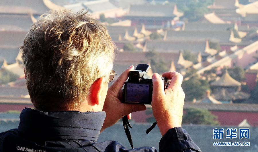 3月10日，一位外国游客在景山公园山顶拍摄故宫。近日，北京天气转暖，大批国内外游客来到北京参观游览。