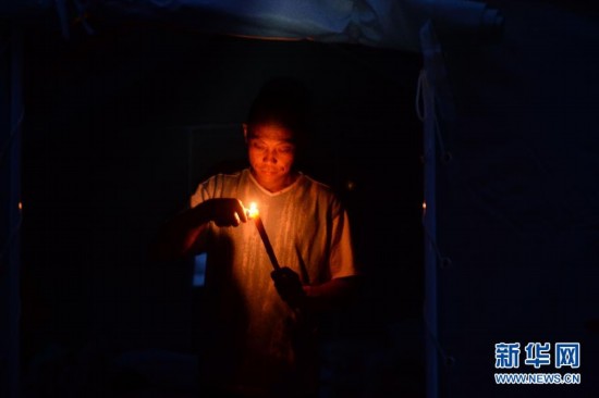 4月26日，芦山县龙门乡隆兴村村民张德文在帐篷中点燃香烛。他的妻子在地震中不幸遇难。