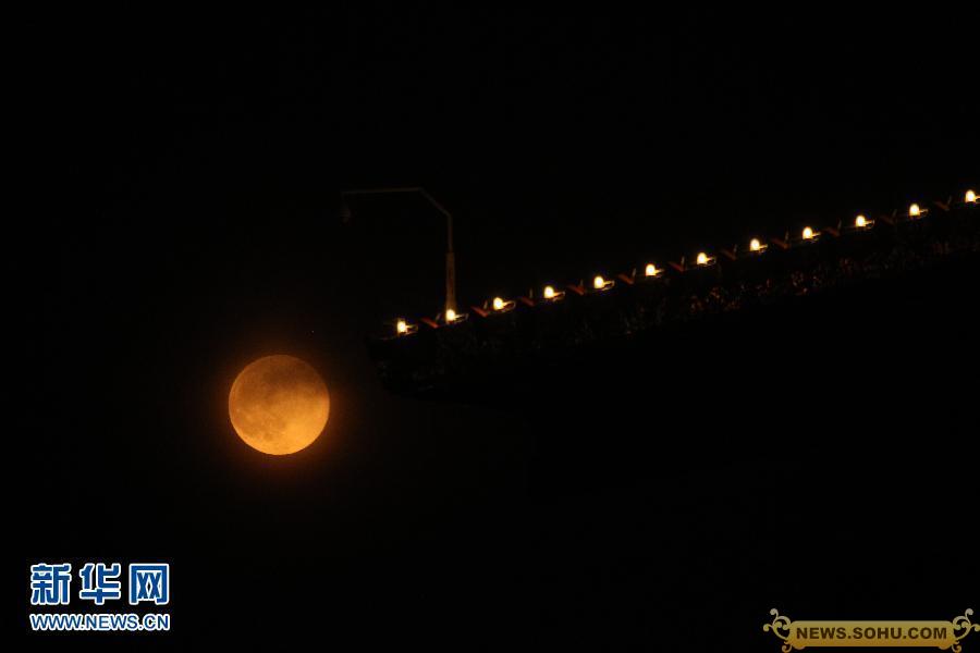 2013年6月23日晚，北京上空的圆月与建筑物上的灯光相互映衬。
