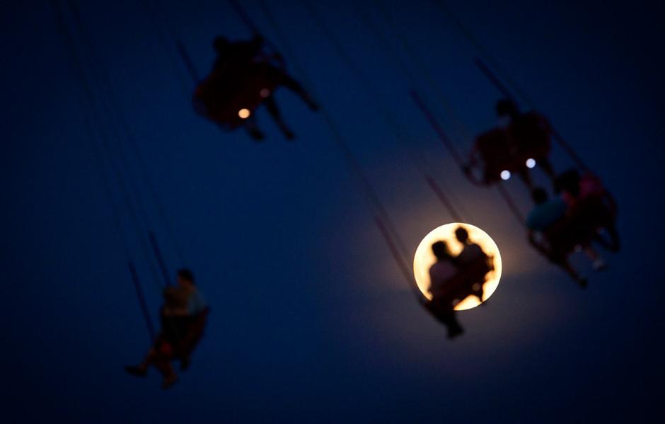 当地时间2013年6月22日，美国康尼岛，人们在月色下游玩。