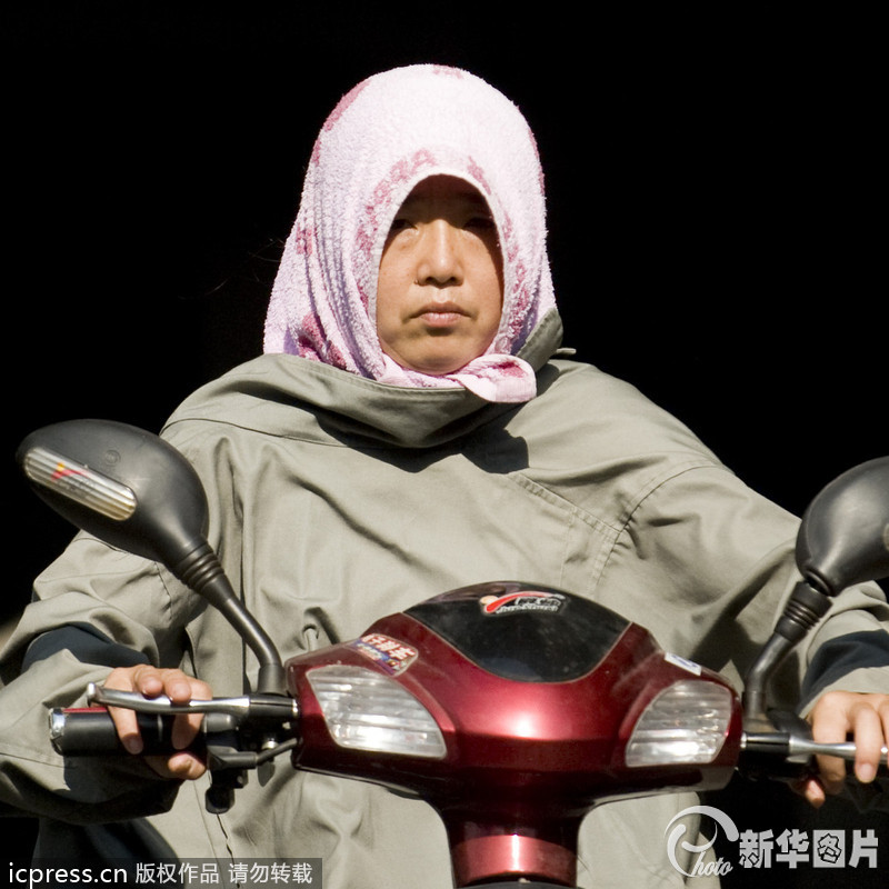 2013年7月24日，在杭州市中河路上，全副武装出行的杭州市民。被民间列为“四大火炉”的杭州热到喷火，杭州市气象台24日发布今年首个高温红色预警，最高温度将达40.4℃。