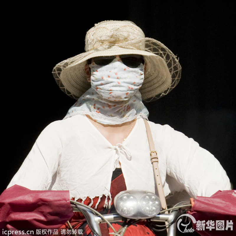 2013年7月24日，在杭州市中河路上，全副武装出行的杭州市民。被民间列为“四大火炉”的杭州热到喷火，杭州市气象台24日发布今年首个高温红色预警，最高温度将达40.4℃。