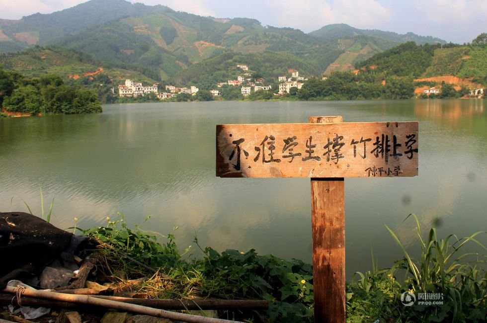 2013年9月8日，广西藤县古龙镇陈平村小学陈山分校通往水库的路上，一块告示牌上写着“不准学生撑竹排上学”。