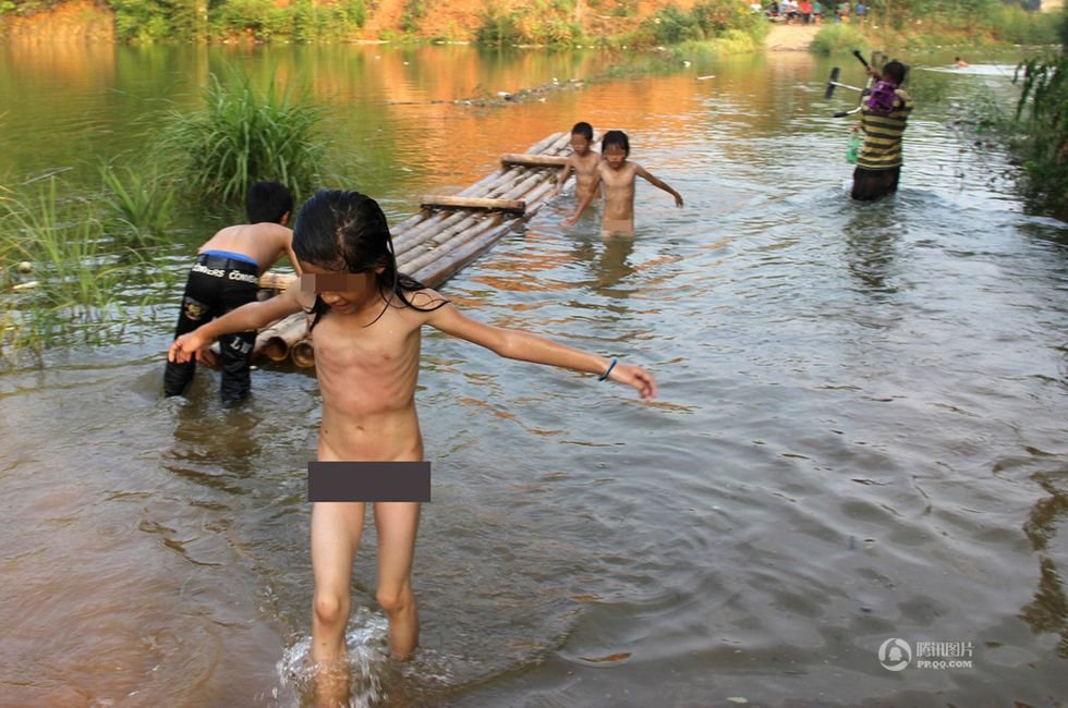 2013年9月8日，广西藤县古龙镇陈平村小学陈山分校通往那龙组的道路上，孩子们在家长的带领下脱衣涉水而过。