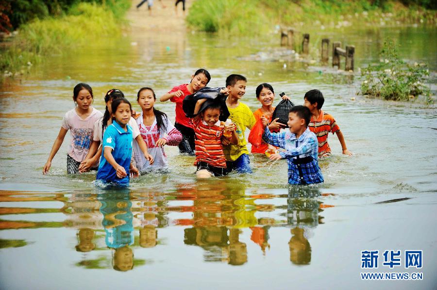 9月9日，在广西藤县古龙镇陈平村小学通往那龙组的桥上，放学回家的孩子们涉水通过桥面。