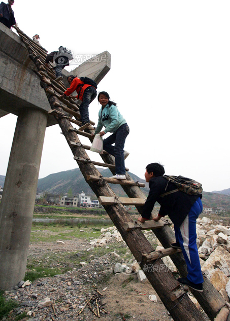 2009年4月10日，陕西丹凤，小学生们爬天梯上学。这里之前修建高速公路时曾计划修建一座桥以方便渡河，但公路通车后，桥却只留半截不修了。无奈之下，村民只好绑了这个天梯。