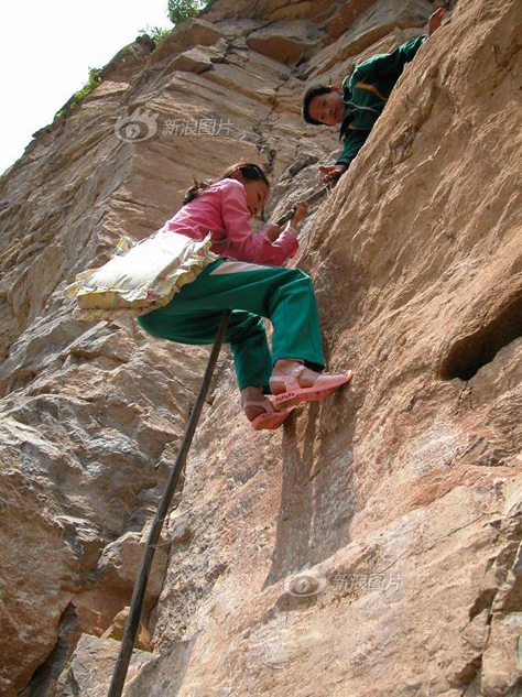 2003年5月19日，山东枣庄市齐村镇浪涛村的孩子们攀下近30米高的悬崖，前往两公里外的学校上学。