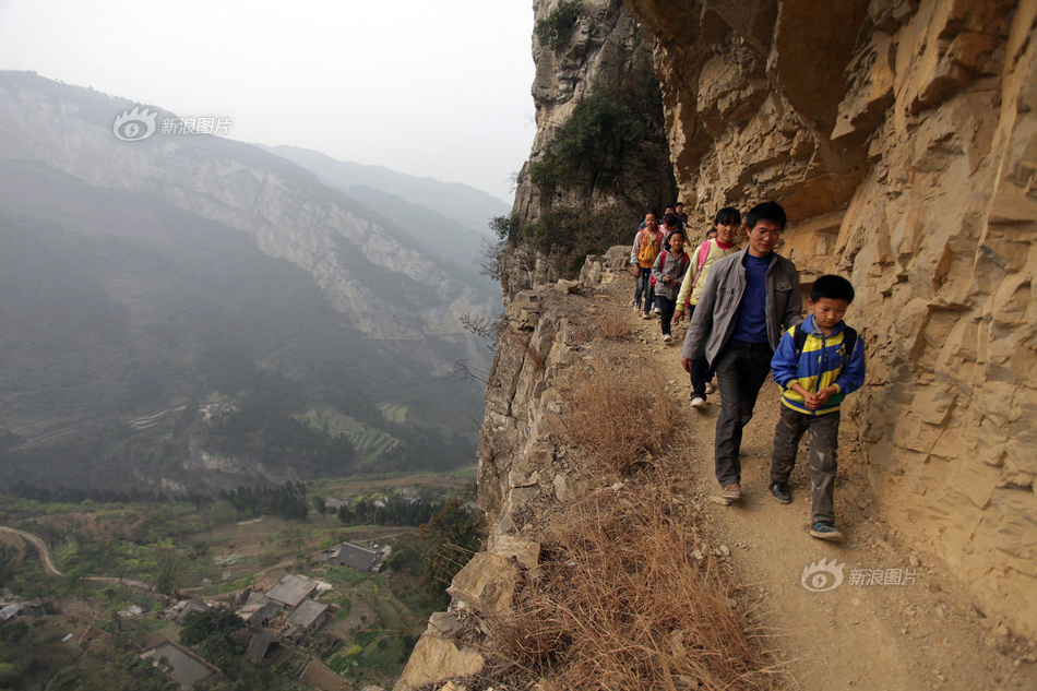 2013年3月11日，贵州毕节地区，半坡小学校长护送学生走过悬崖峭壁上的小路。