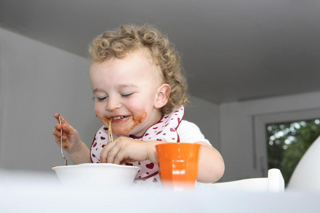 乖乖的宝宝自己吃饭，真的是很独立的小萌娃啊，自己动手吃饭的小宝宝表情也是很萌哟。妈妈们可以培养小孩子自己吃饭的意识哟，这样能减少自己的负担，也让小宝宝更加的独立呢。