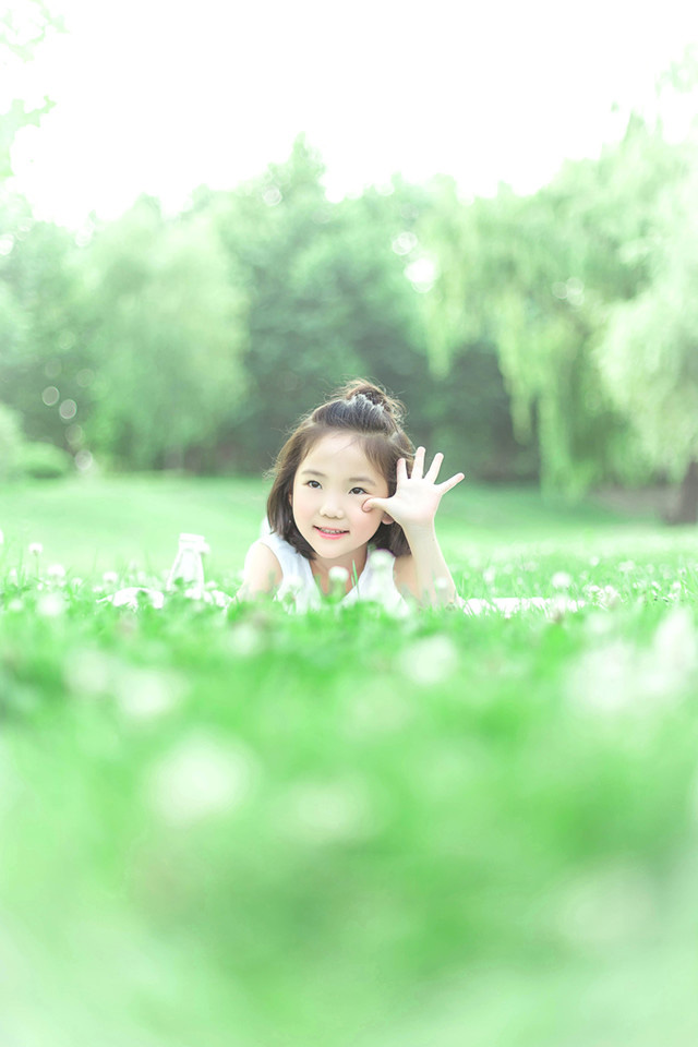 绿油油的草地上可爱的小女孩，白色的裙子，躺在草坪上的她笑容纯真美好，短发俏皮可爱。写真散发出的生机勃勃的状态让人感受到生命的美好。超级的舒服啊~~