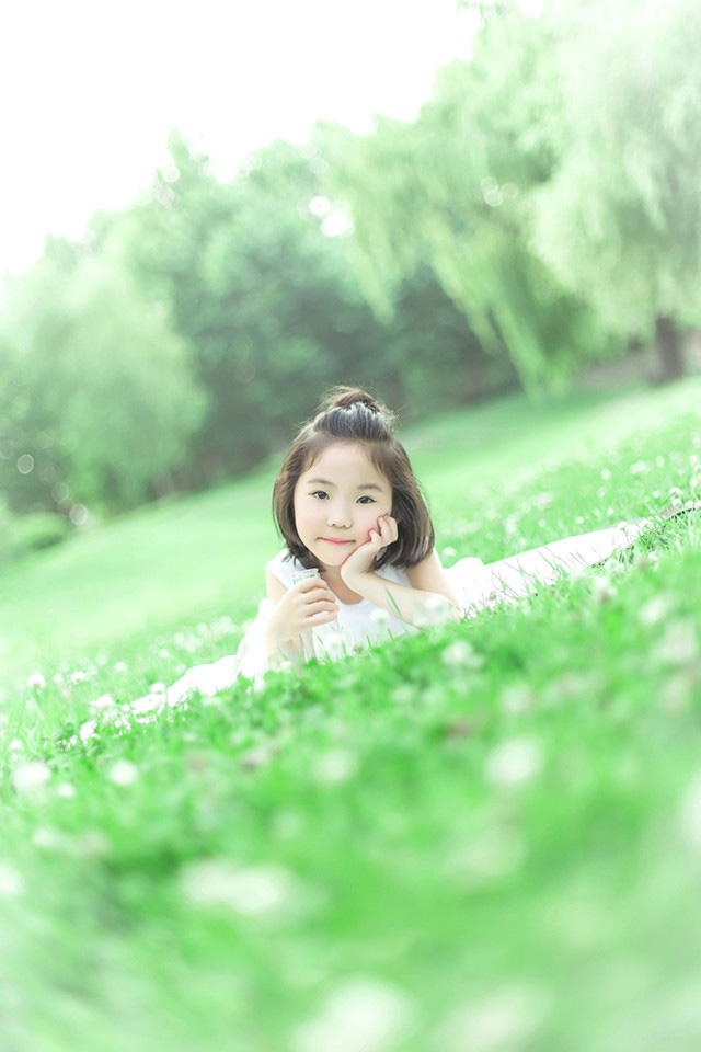 绿油油的草地上可爱的小女孩，白色的裙子，躺在草坪上的她笑容纯真美好，短发俏皮可爱。写真散发出的生机勃勃的状态让人感受到生命的美好。超级的舒服啊~~