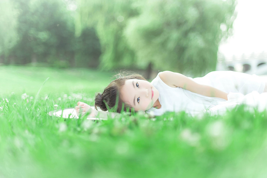 绿油油的草地上可爱的小女孩，白色的裙子，躺在草坪上的她笑容纯真美好，短发俏皮可爱。写真散发出的生机勃勃的状态让人感受到生命的美好。超级的舒服啊~~
